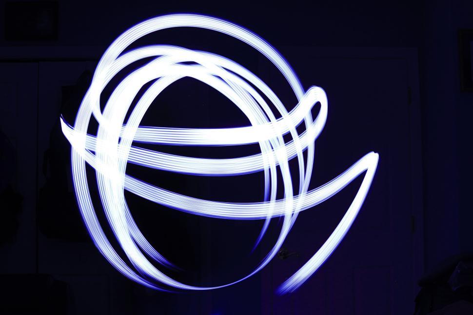 Free Image of Light trails create abstract patterns in dark space 