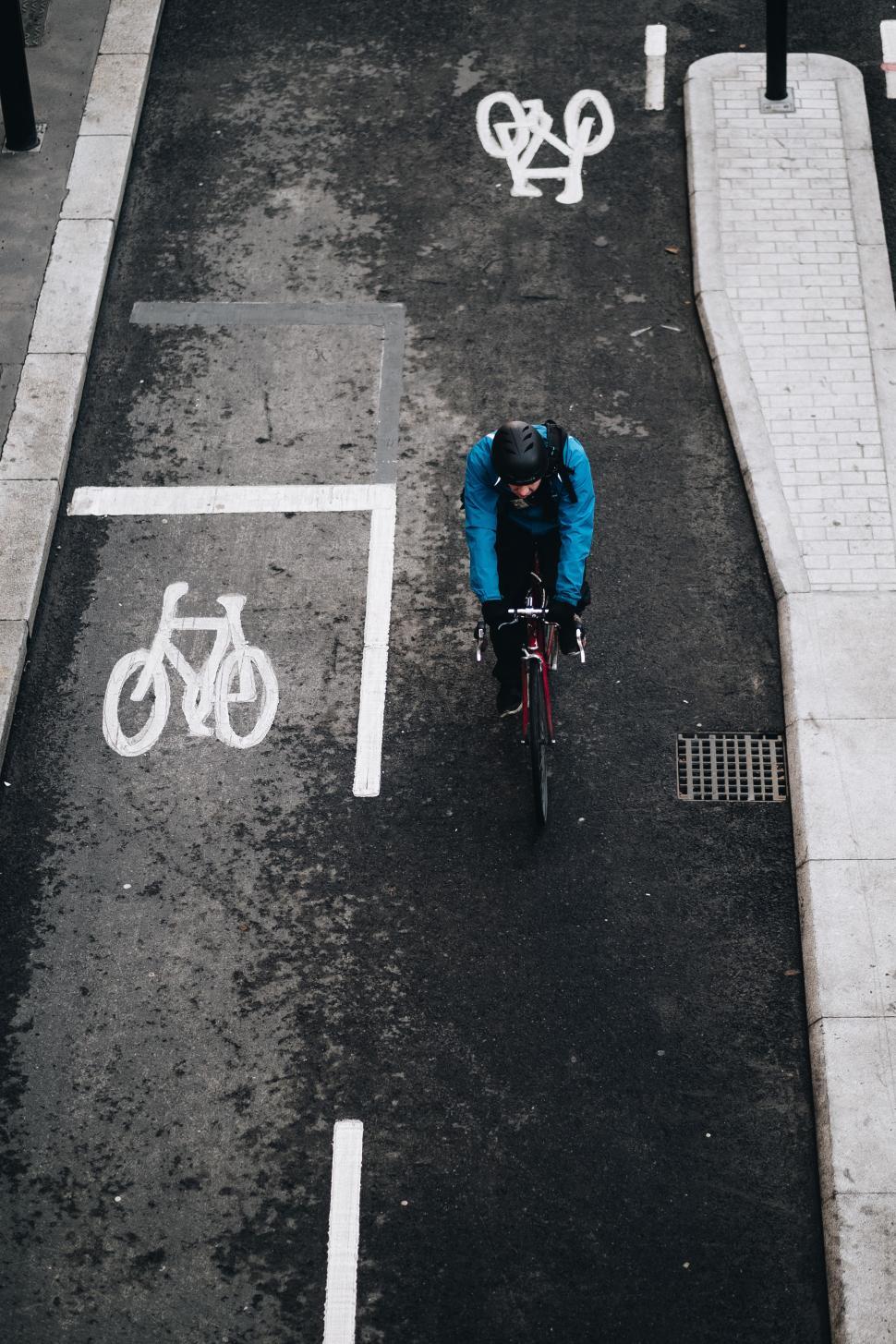Free Image of Cyclist riding through urban bike lane in rainy weather 