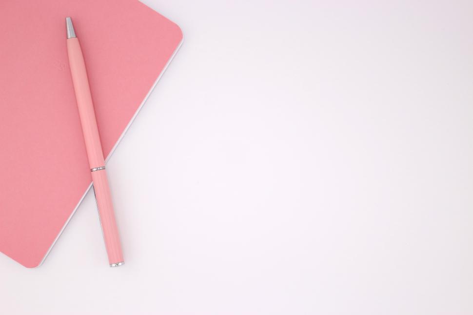 Free Image of Stylish pink notebook with matching pen placed on a light surface 