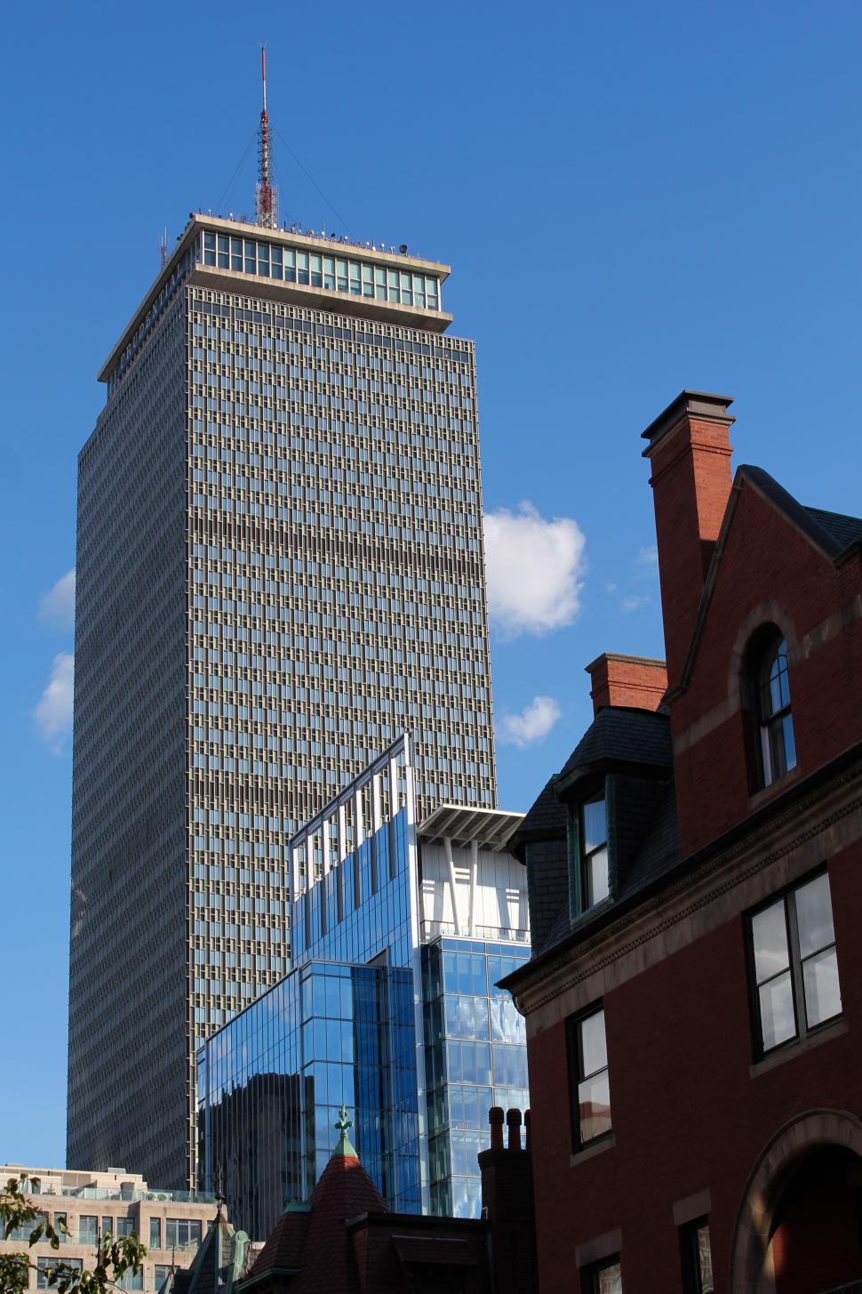 Free Image of Tall modern skyscraper rises above historic buildings 