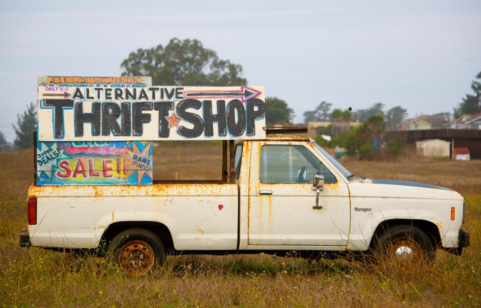 Free Image of Alternative thrift shop sign on vintage pickup truck in field setting 
