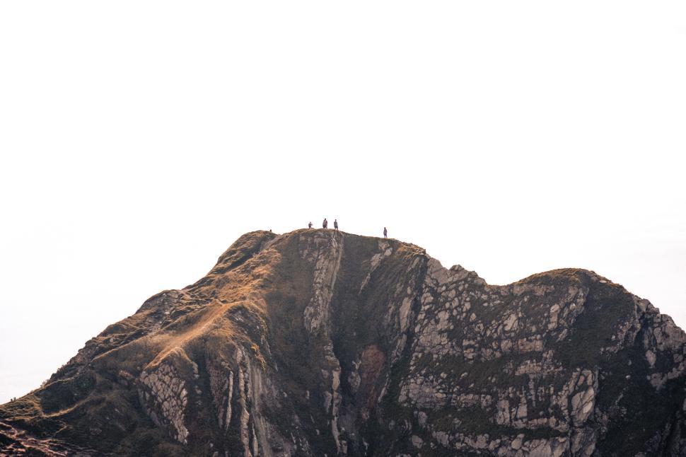 Free Image of Hikers reach the summit of a rugged mountain peak 