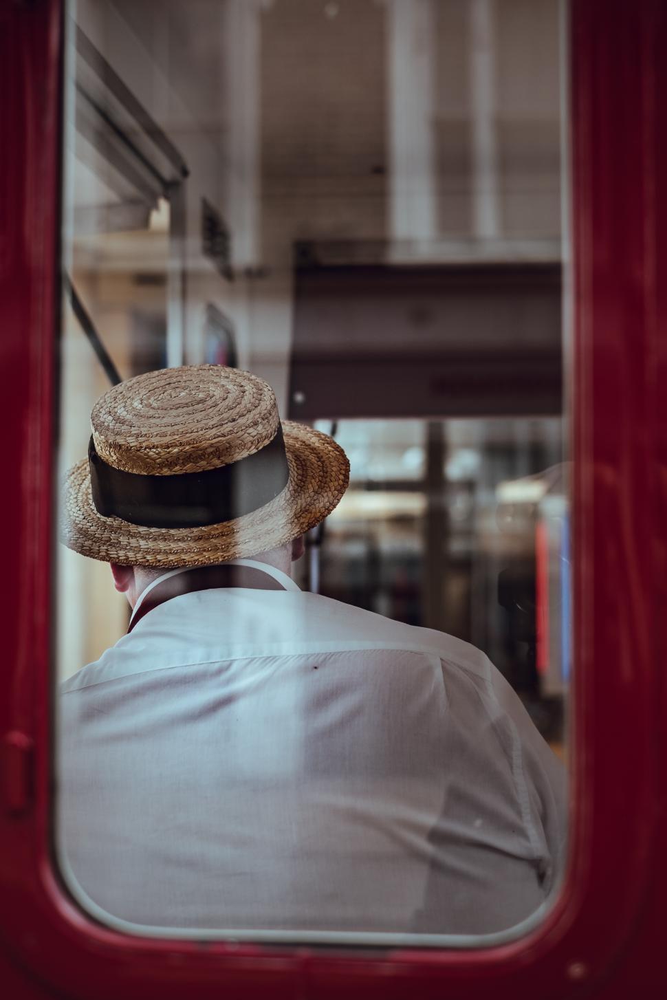 Free Image of Man wearing a straw hat sitting in a public transport vehicle 