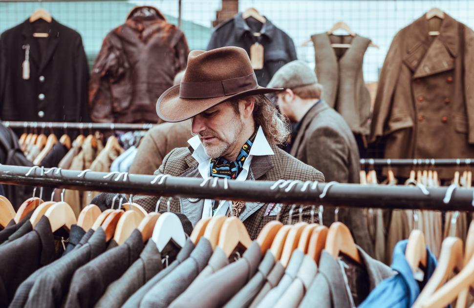 Free Image of Vintage market visit reveals stylish men browsing clothing racks 