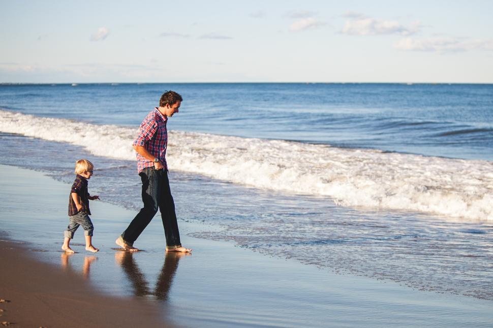 Free Image of Father and son walking by the ocean shore together 