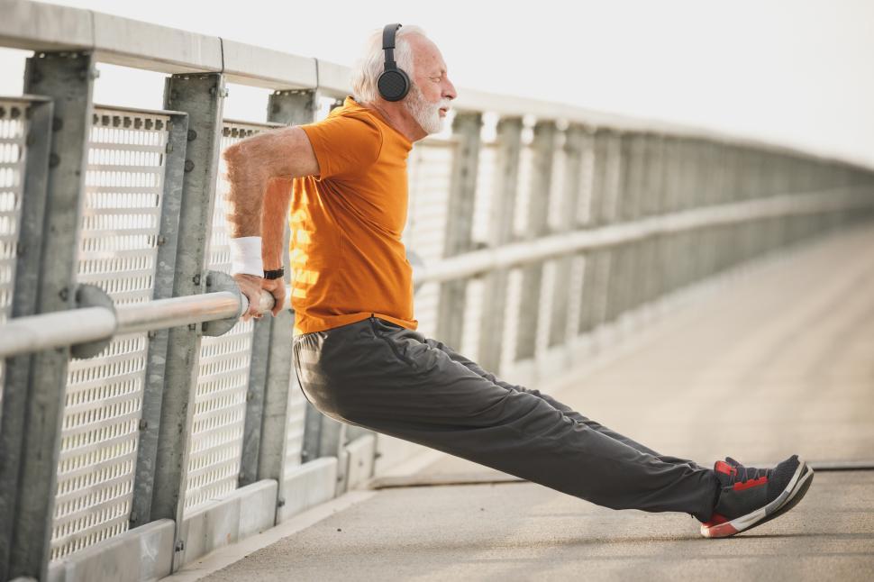 Free Image of Senior man exercising on a bridge while listening to music 
