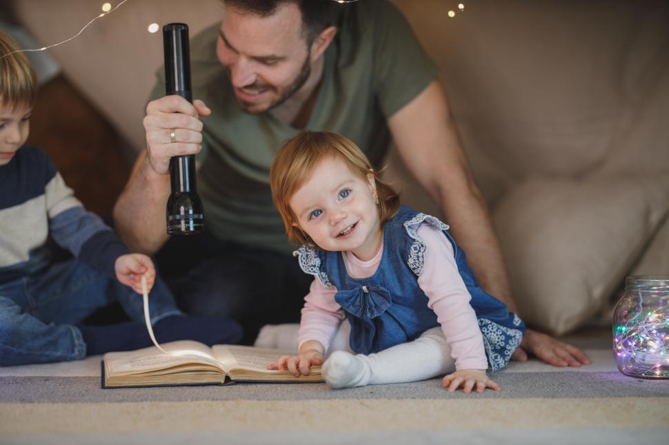 Free Image of Family reading time with flashlight in cozy indoor setting 