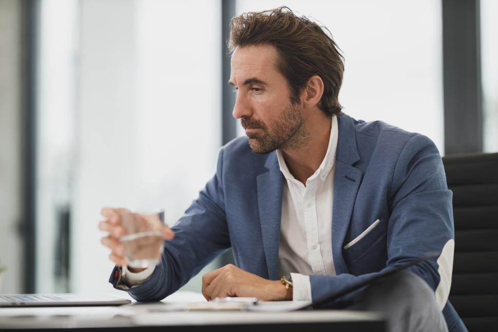 Free Image of Businessman in a suit contemplating decisions in modern office 
