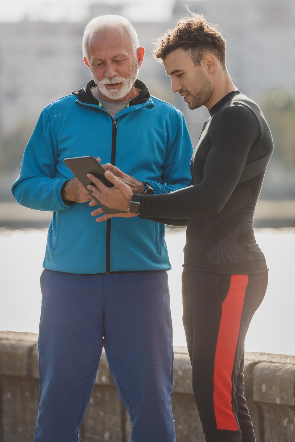 Free Image of Coaching session by the river with two men discussing fitness plans 