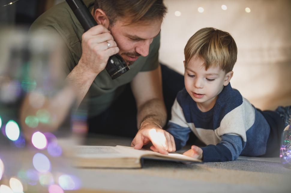 Free Image of Father and child reading together with flashlight in cozy atmosphere 