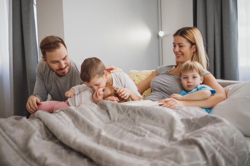 Free Image of Family enjoying cozy morning together in bed with kids 