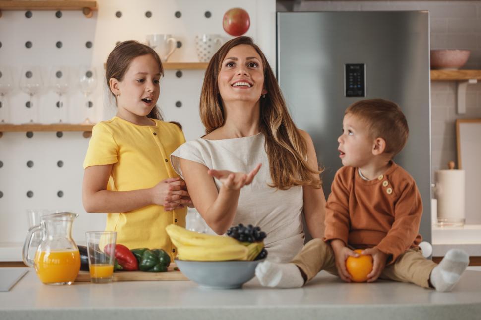 Free Image of Family enjoying playful moment in kitchen with fruits and laughter 