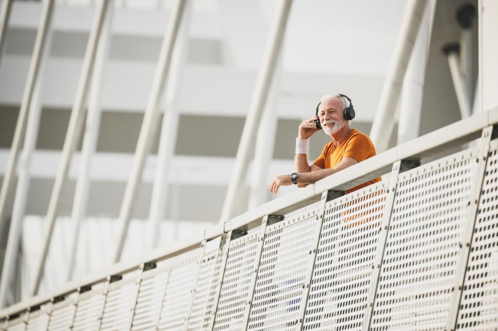 Free Image of Elderly man enjoying music on a bridge in a modern city 