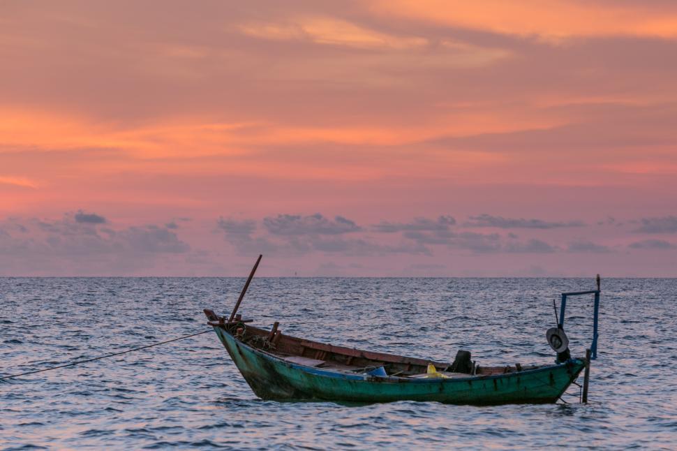Free Image of Fishing boat anchored in calm waters at sunset 