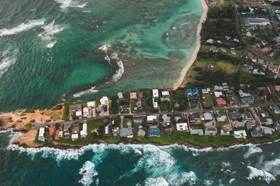 Free Image of Coastal overview of a serene seaside town with homes and ocean waves 