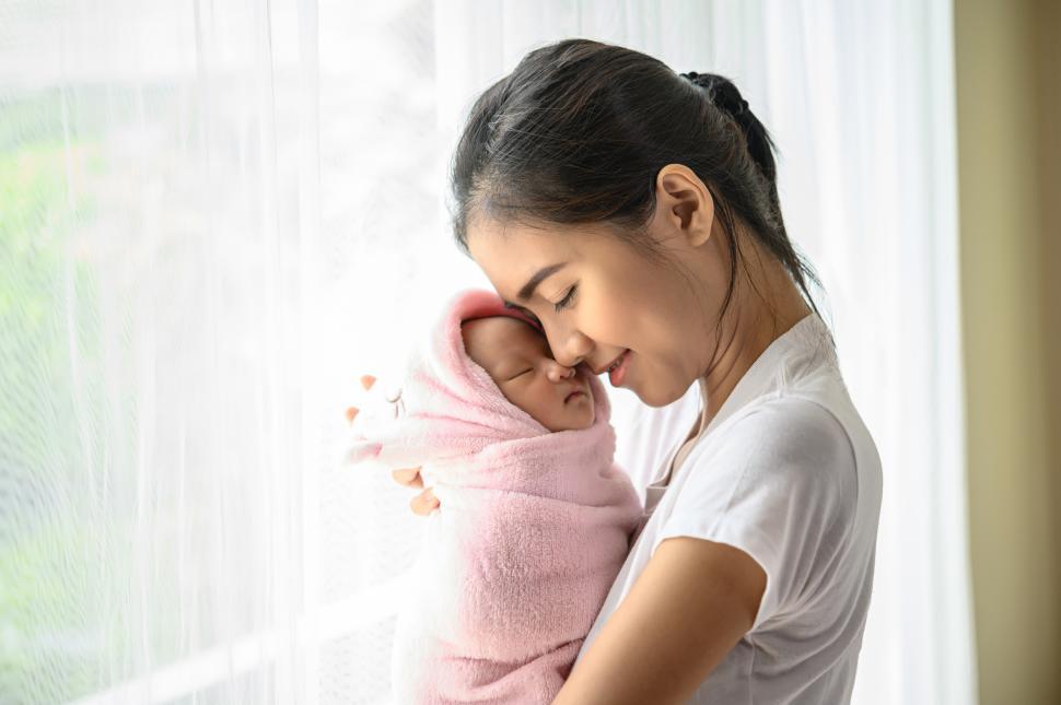 Free Image of The newborn baby sleeping in the embrace of the mother and the nose collided. 