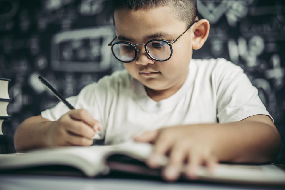 Free Image of A boy with glasses man writing in the classroom 
