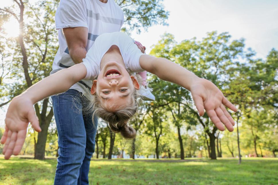 Free Image of Child enjoys playful moment with adult in sunny park 