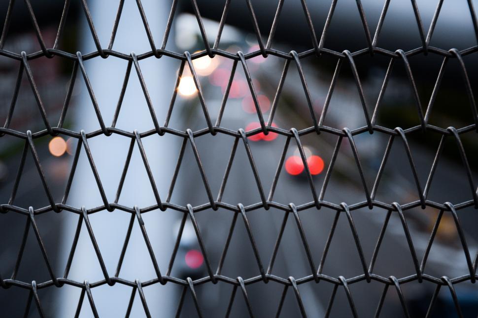 Free Image of Traffic view through a metal fence at dusk 