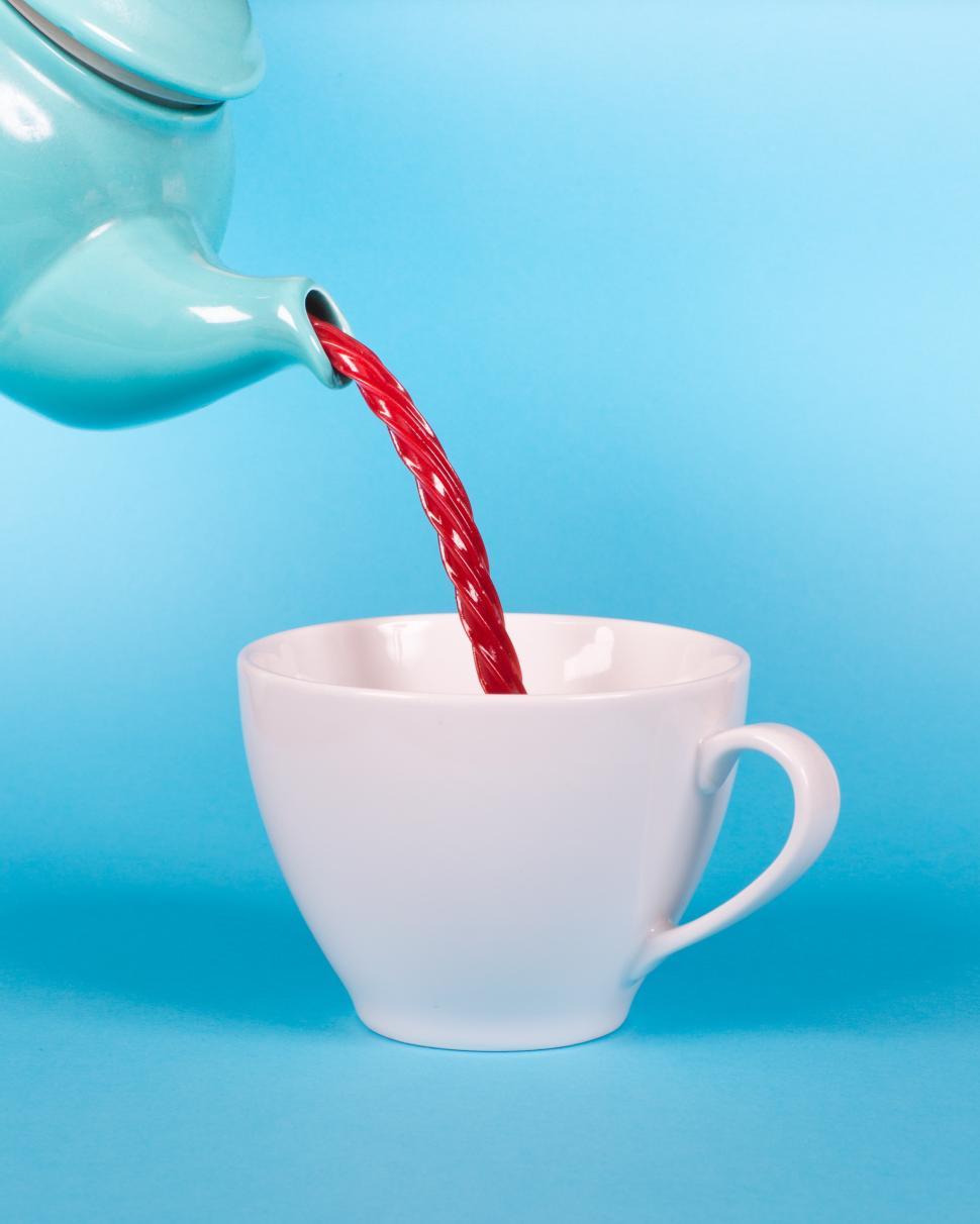 Free Image of Hot tea pours from a turquoise kettle into a white cup on a blue background 