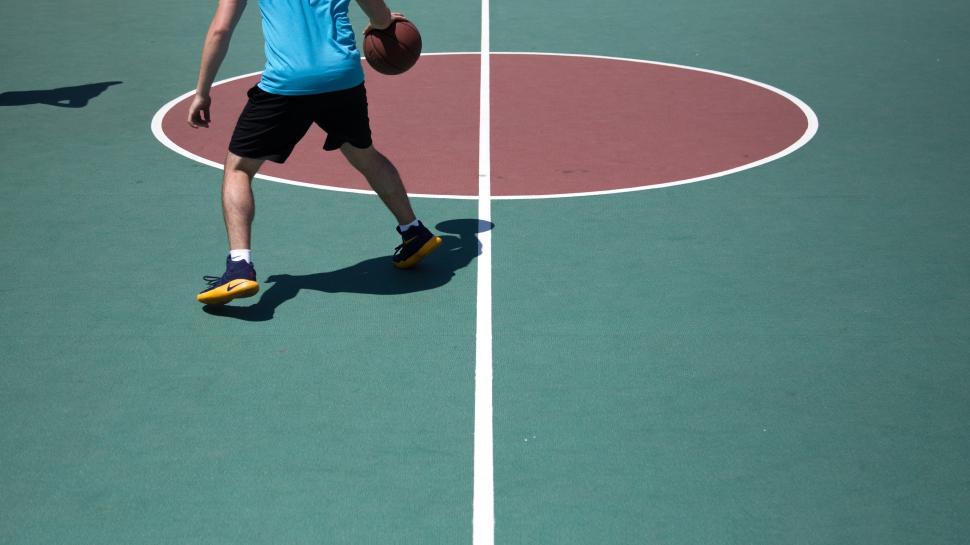 Free Image of Basketball players practice dribbling on a court during daylight hours 