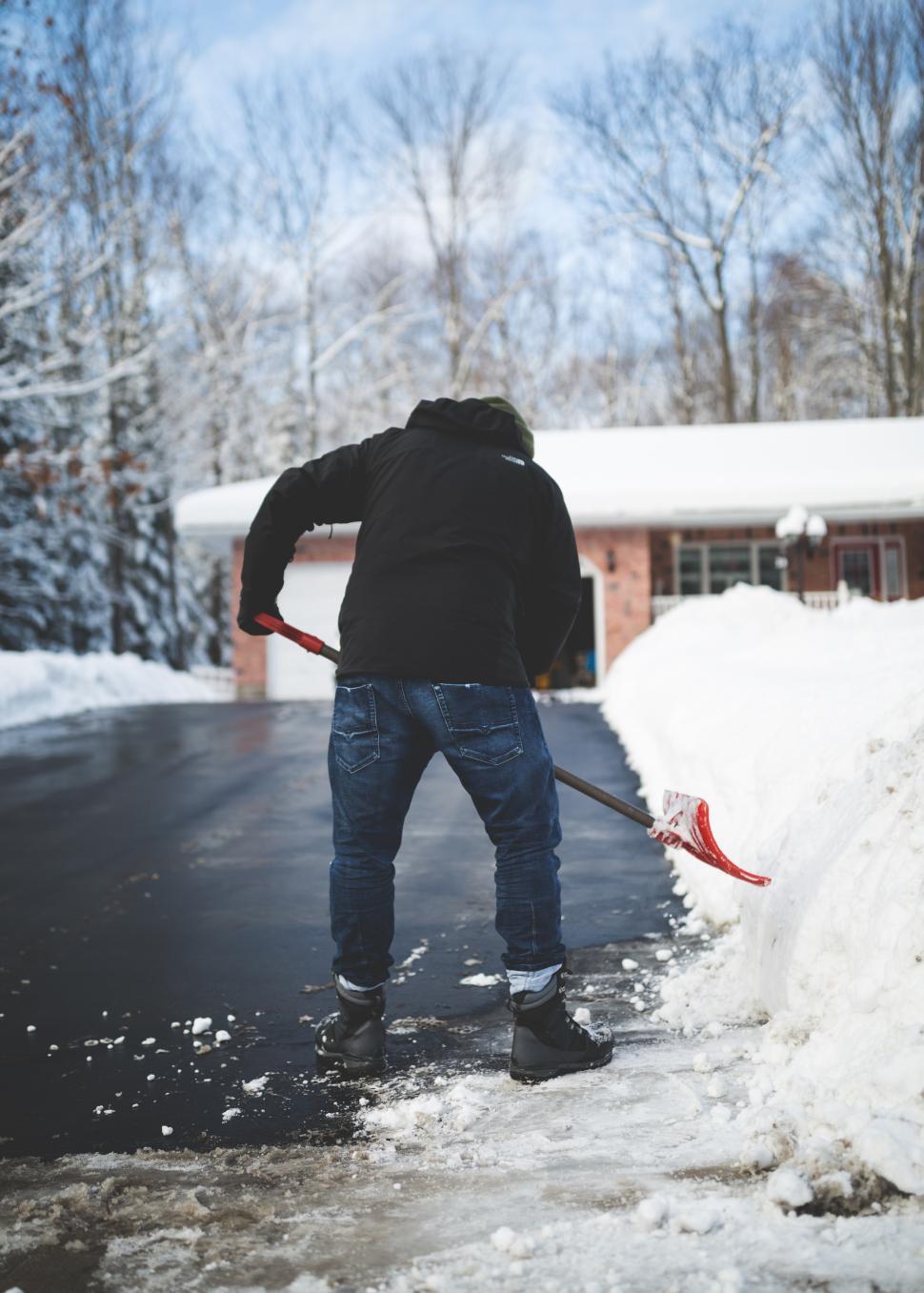 Free Image of Shoveling snow from a driveway in a residential area during winter 