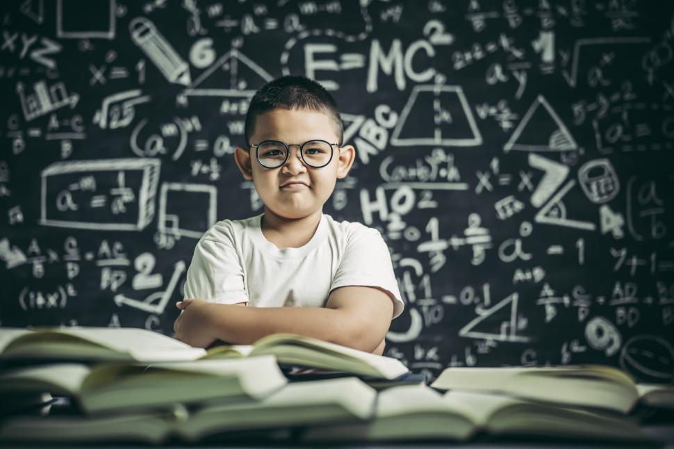 Free Image of A boy with glasses sitting in the classroom reading 