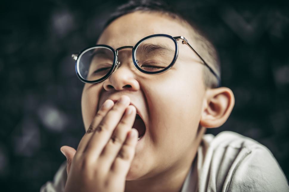 Free Image of A boy with glasses studying and drowsy. 