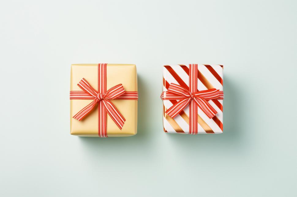 Free Image of Presents wrapped in gold and striped paper on light background 