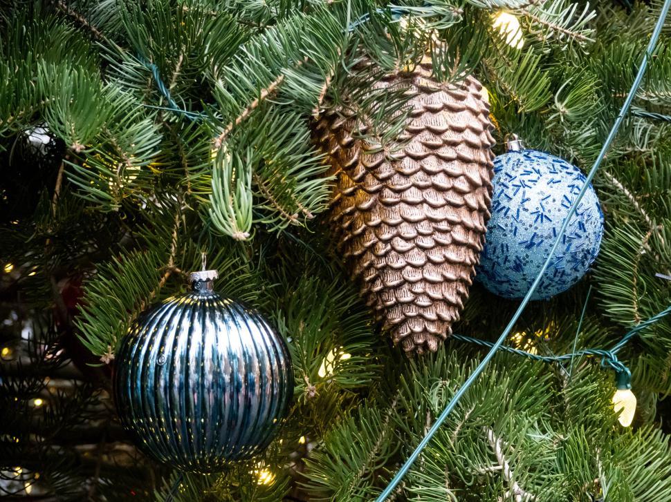 Free Image of Sparkling Christmas ornaments and pinecones adorn a festive tree 