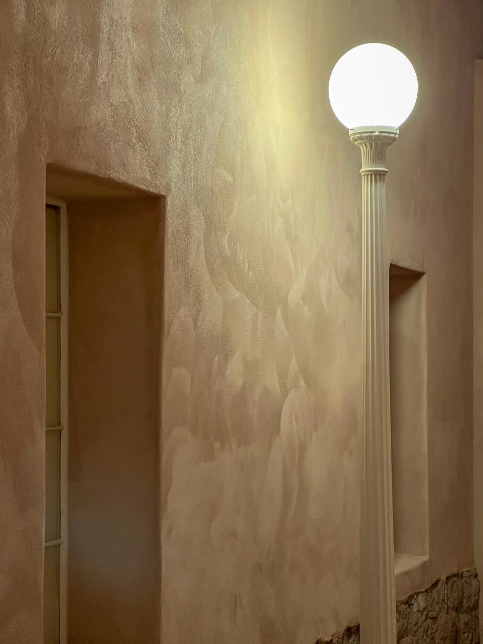 Free Image of Lighting fixture casts warm glow on textured wall in modern space 