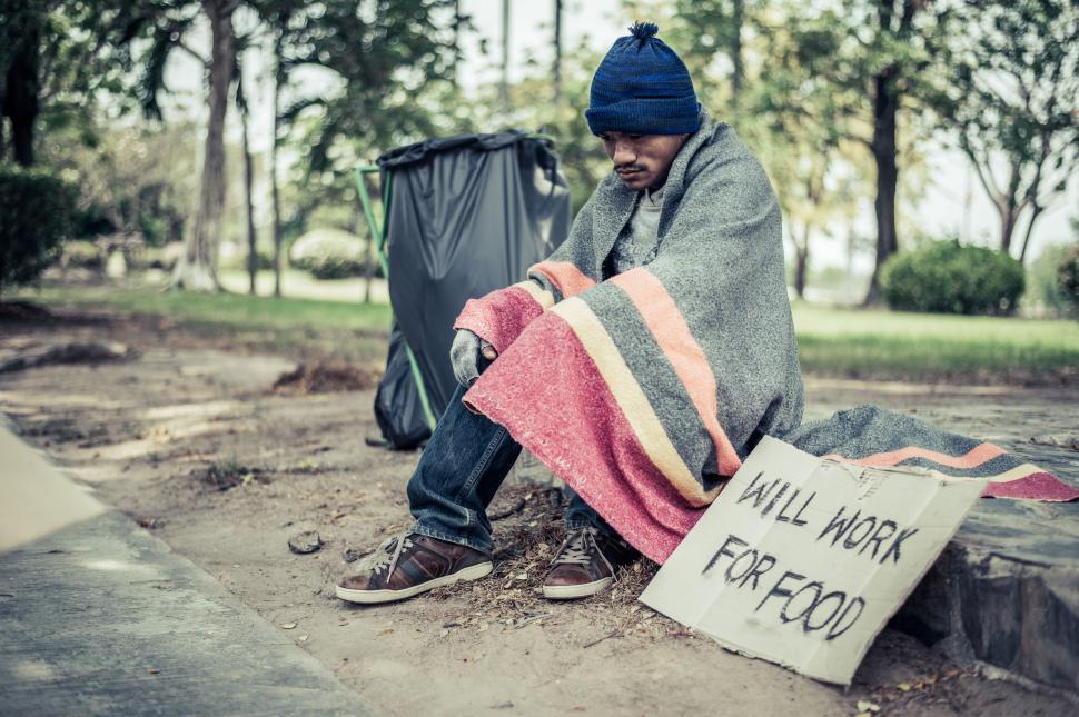 Free Image of Beggars, wrapped in cloth, then wearing a hat and sitting down beside the road. 