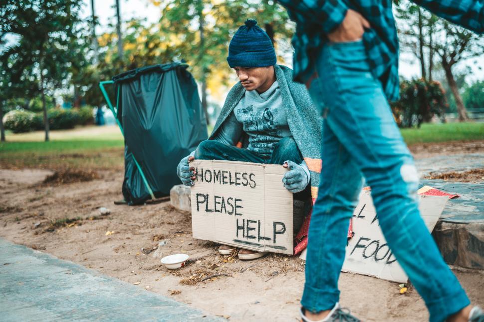Free Image of Beggars wrapped in cloth and then put on a hat and sat down beside the street and someone gave money. 