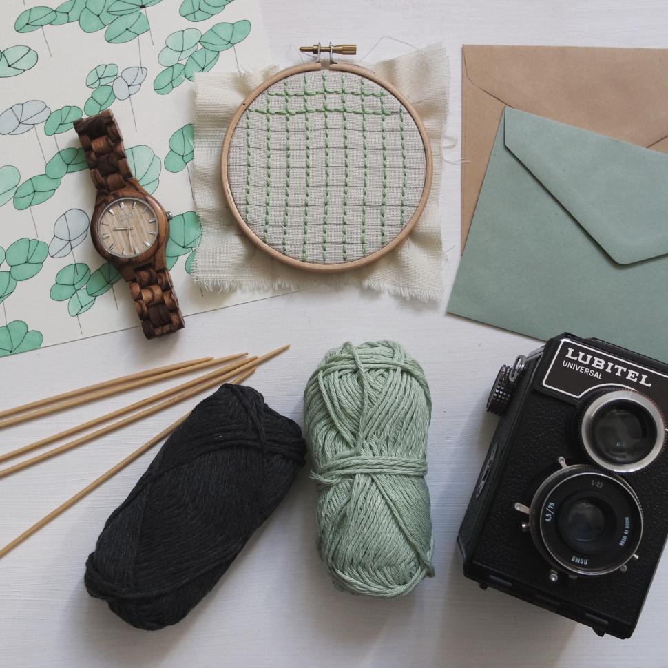 Free Image of Crafting session with embroidery, yarn, and vintage camera on table 