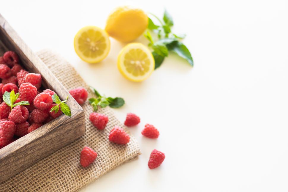Free Image of Fresh raspberries and lemons on a rustic table 