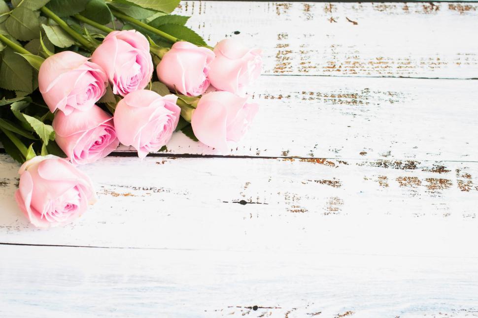 Free Image of Elegant pink roses arranged on a rustic wooden surface 
