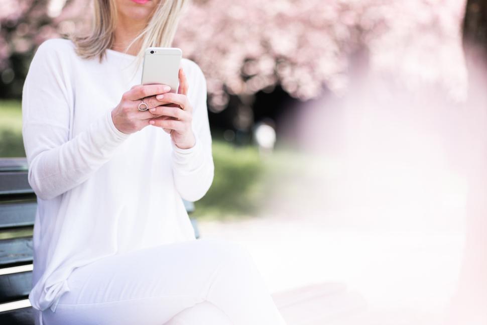 Free Image of Woman enjoying springtime while using smartphone in park 