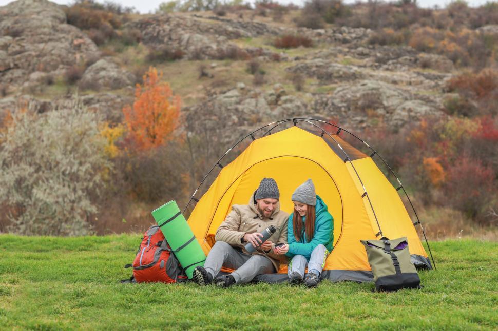 Free Image of Couple enjoys warm drinks while camping in nature during autumn 