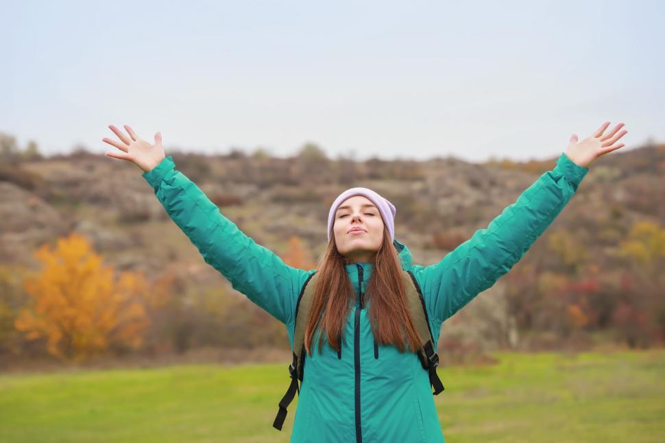Free Image of Hiking in the countryside with arms raised in celebration 