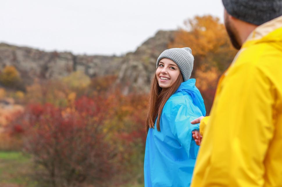 Free Image of Smiling woman in blue raincoat enjoys autumn hike with friend 