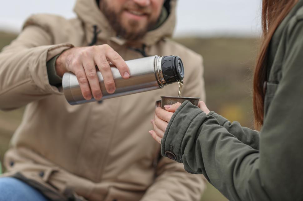 Free Image of Couple enjoying warm beverages outdoors during a chilly afternoon 
