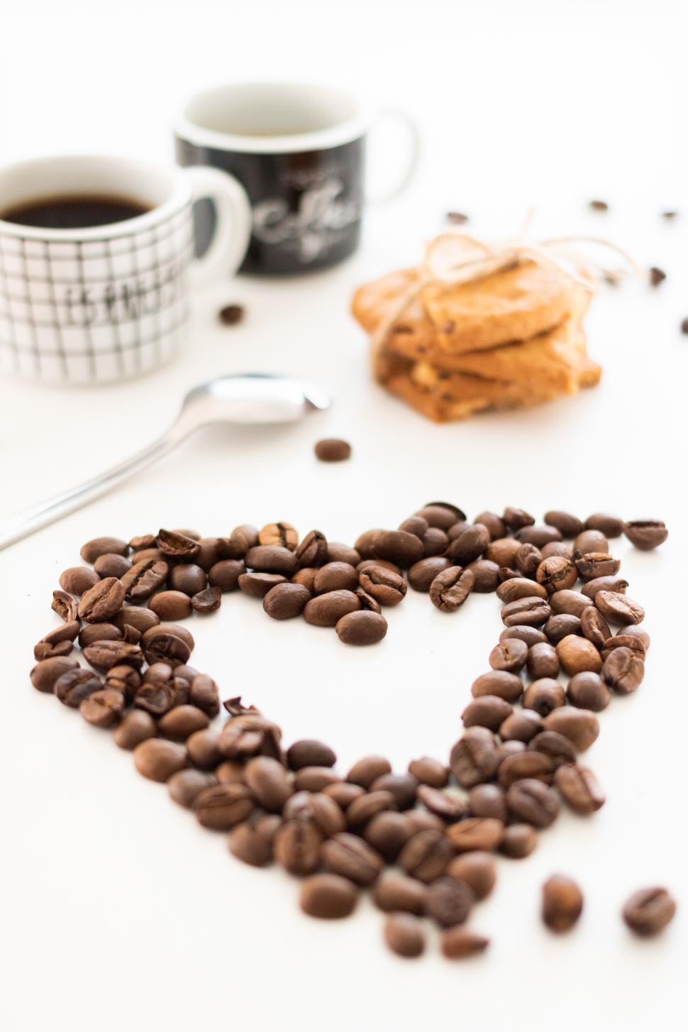 Free Image of Coffee beans arranged in heart shape with mugs nearby 