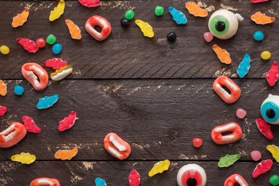 Free Image of Colorful candy scattered on a rustic wooden table 