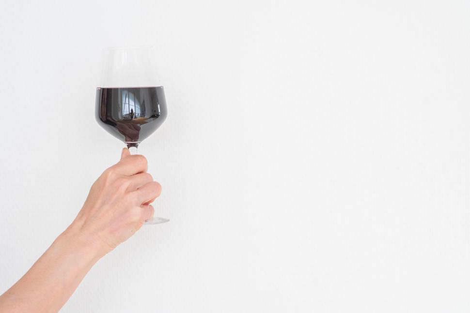 Free Image of Hand holding a wine glass against a white background 