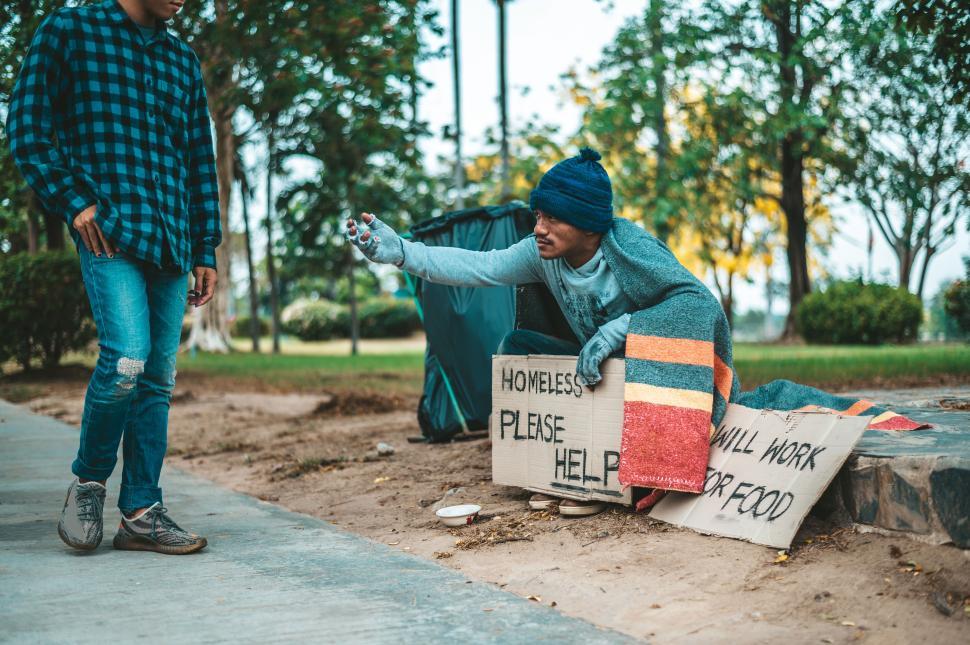 Free Image of Beggars wrapped in cloth and then put on a hat and sat down beside the street and someone gave money. 