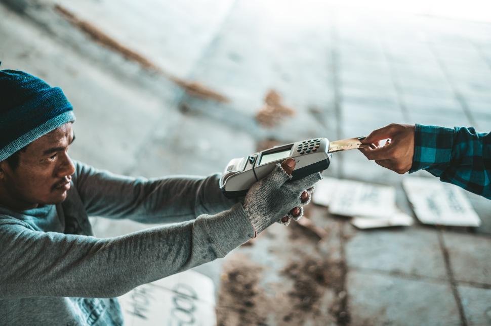 Free Image of Beggars sitting under the overpass with a credit card and credit card swipe machine 