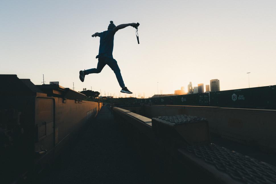 Free Image of Urban jumper performs daring leap at sunset in city 