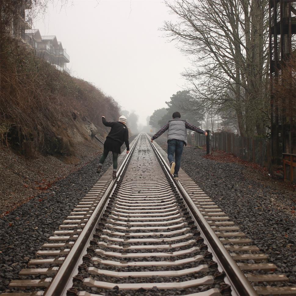 Free Image of Friends enjoy a foggy walk along the railway tracks 