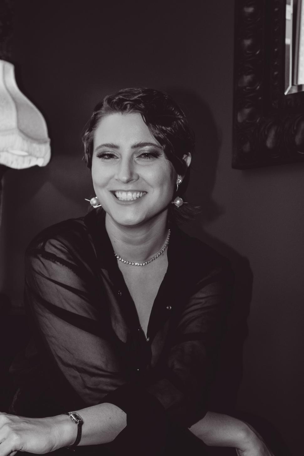 Free Image of Smiling woman in a dark setting poses casually with elegance and charm 