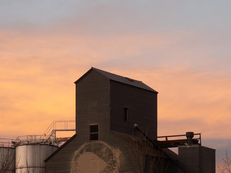 Free Image of Silhouette of a vintage farm building against a colorful sunset sky in rural area 